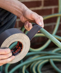 Applying Ferociously Strong Duct Tape One Point Eight Eight Inch By Thirty Five Yard Dark Gunmetal Gray to hose for outdoor repair