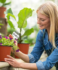 Woman planting in 40 Pack 4 Inch Plant Nursery Pots With Drainage Holes For Seedlings Cuttings And Succulents Reusable Plastic Seed Starting Pots