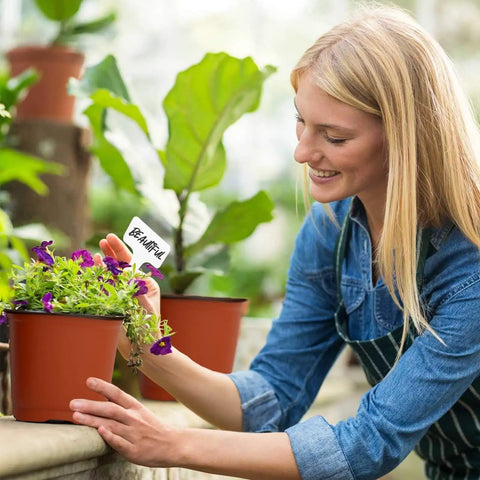 Woman planting in 40 Pack 4 Inch Plant Nursery Pots With Drainage Holes For Seedlings Cuttings And Succulents Reusable Plastic Seed Starting Pots