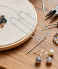 Rugged Heavy Duty Iron Safety Pins Pack Of 50 for thick sweaters on wooden table with beads and tools.