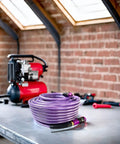One Quarter Inch Polyurethane Air Hose Reinforced Lightweight Compressor Tubing Finish Safe And Slick Built Tough With Zero Drag For Auto Repair And Real Shop Grind Daily coiled on a workbench next to a compressor.