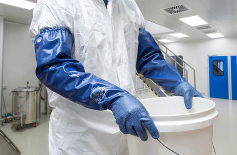 Person wearing full arm 26 inch nitrile safety glove with biodegradable coating, chemical resistant, handling bucket.