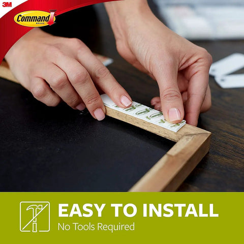 Hands attaching Damage Free Picture Hanging Strips For Walls No Tools Needed Medium And Large White Mounts to wood frame. Easy installation.