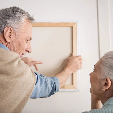 Elderly couple using All In One 276 Piece Picture Hanging Kit With Hangers And Hardware to mount frame on wall