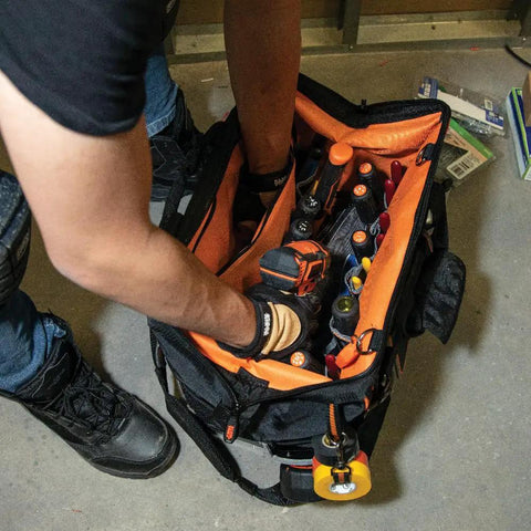 Worker using Tradesman Pro Wide Open Tool Bag With 1680 Ballistic Weave Molded Bottom Detachable Shoulder Strap Stay Open Top