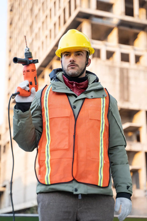 Man wearing Snap Up These Super Bright 10 Pack High Visibility Safety Vests With One Inch Reflective Strips holding a power tool.