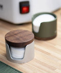 Slick Swivel Coffee Filter Paper Holder And Brewing Tool Caddy in dark green wood and metal, holding filter papers on a wooden counter.