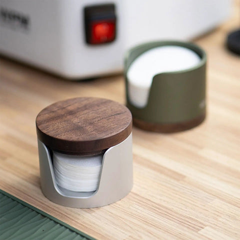Slick Swivel Coffee Filter Paper Holder And Brewing Tool Caddy in dark green wood and metal, holding filter papers on a wooden counter.