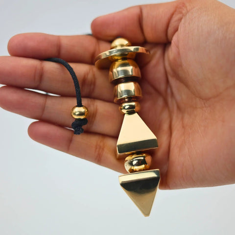 Hand holding Brass Pendulum For Dowsing And Energy Healing Reiki And Chakra Balancing Tool Divination Accessory Crown Light Gift