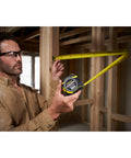 Person using Fatmax Autolock Tape Measure 8m Metric Only Yellow Black, Reverse Lock for one-handed control in construction setting