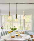 Mid Century Modern Large Gold Globe Pendant Light Plug In With Brushed Brass Finish And White Glass Minimalist Sphere Hanging Lamp Easy Cord Plug In Setup Fourteen Point Seven Six Foot Cord For Flexible Height And Room Essentials shown in dining area.