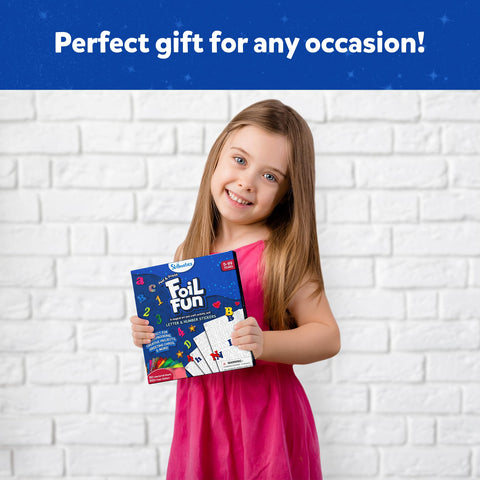 Child holding Foil Fun Letter And Number Sticker Set For Mess Free Arts And Crafts Projects in red dress against brick wall.