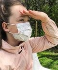 Girl wearing Kids Disposable Face Masks For Girls Aged 6 To 12, 10 Pack, Breathable Protective Masks With Fun Print Designs in garden