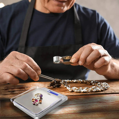 Jeweler using Compact 500g Digital Gram Scale With 0.01g Precision For Jewelry And Kitchen Use, necklace and gemstones shown.