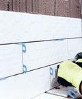 Massive 1600 Pack Plastic U Shaped Tile Spacers For Leveling in blue during DIY tile installation on a wall.