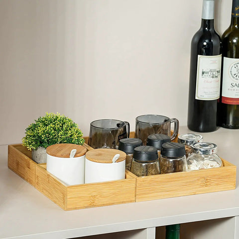 Bamboo Drawer Organizer Set Of 9 For Kitchen And Office holding mugs, jars, and containers, on a counter with wine bottles in the background.