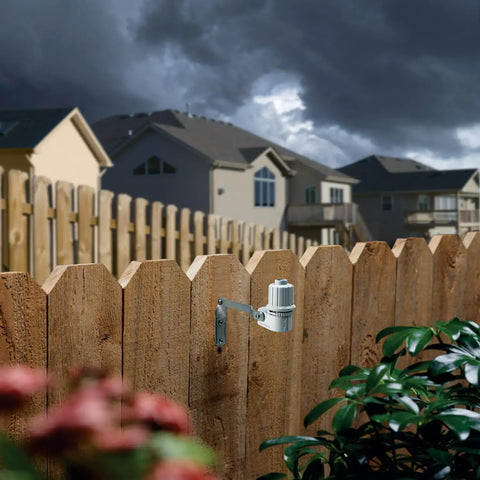 CPRSDBEX Wired Rain Sensor with mounting bracket on a wooden fence for sprinkler systems, cloudy sky background