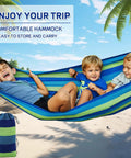 Children playing in a blue and green striped hammock on a beach with palm trees
