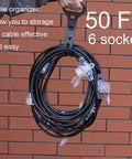 50Ft Outdoor Power Extension Cord With Seven NEMA 5 15R Outlets coiled with handle against brick wall