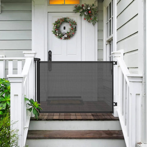 Retractable Baby Gate For Wide Openings Up To 71 Inches, 33 Inches Tall set up on a porch with holiday decor.