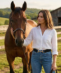 Woman in white shirt wearing Elastic Equestrian Belt For Women With Wide Horse Riding Strap and Buckle, standing with a horse.