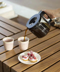 1.25L Glass Carafe for KBG Brewers, Clear Black Version, pouring coffee into cups on a wooden table with desserts