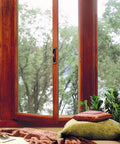 Cozy window nook with pillows and a view of trees outside.