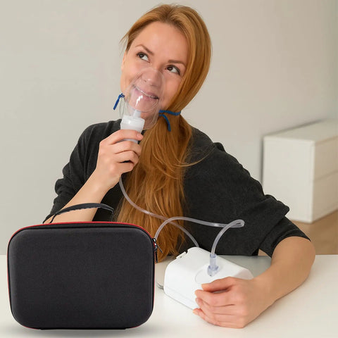 Woman using desktop nebulizer with red hard case for nebulizer and accessories nearby, travel ready storage bag.
