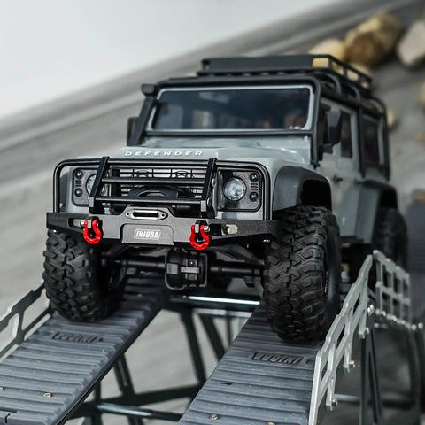 Aluminum RC Bumper Set For 1/18 TRX4M Defender on rocky slope, shows CNC Front 37G Bumper, LED lights, removable tow hitch in action.