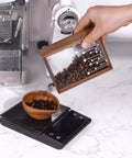 Handcrafted Solid Wood Coffee Bean Jar With Reliable One Way Degassing Valve And Heavy Duty Rubber Seal Keeps Your Daily Grind Fresh As Heck And Ready For Brewing On The Kitchen Counter being used to pour beans into a wooden bowl.
