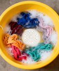 Portable USB Powered Mini Washing Machine For Travel And RV Adventures with colorful clothes spinning in water.