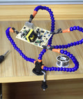 No Sweat Hella Solid Third Hand Soldering Helper With Four Bendable Upright Arms supporting a circuit board on a worktable.
