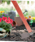 Heavy Duty Stainless Steel Garden Hoe With Ergonomic Wooden Handle Lightweight Planting Tool in use, loosening soil among flowers.