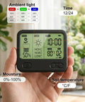 Hand holding expandable twelve zone wireless plant monitor kit with indoor LCD hub displaying soil moisture and temperature data.