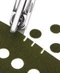 Close-up of Hand Held Slot And Thirteen Millimeter Round Hole Punch Tool 2-In-1 Diy Puncher on green paper