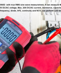 Pro Grade Digital Multimeter With TRMS 6000 Counts Reads 1000V AC DC, 20A Current in use with electrical panel, gloved hand visible