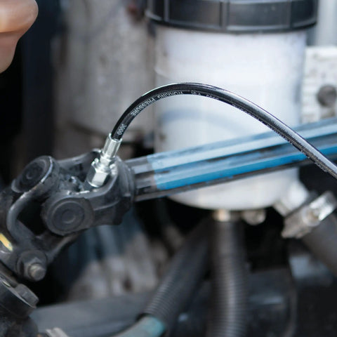 Close-up of Professional Grade 14 Oz Pistol Grip Grease Gun in use, lubricating machinery with smooth pump action.
