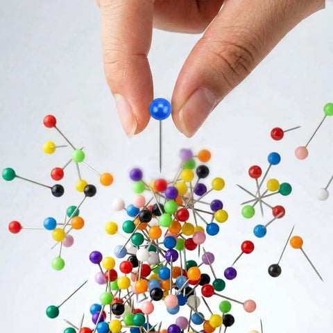 Hand holding a blue Straight Up Go To Multi Color Map Push Pin above colorful pins for travel boards, showcasing 100 markers.