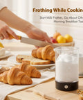 Handheld Cold Foam Frother For Coffee Battery Powered With Two AA One Button Operation on table with croissants and bread