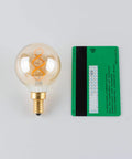Dimmable E12 LED Filament Bulb 4W 40W Equivalent Amber 2200K 300 Lumens G16.5 next to credit card for size comparison