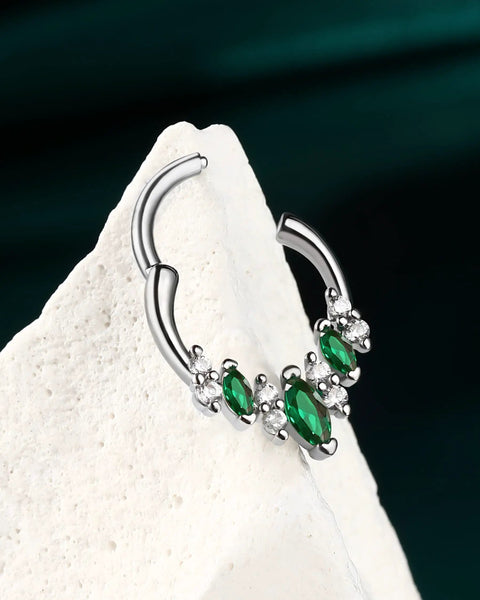 Silver septum ring with green gemstones on white background, showcasing V shape design for helix and daith piercings.