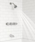 Three Handle Tub And Shower Faucet With Metal Verve Knob Handles In Polished Chrome For A Slick Bath Upgrade Includes 5 Hole Installation Valve And Cartridge Shower Arm And Flange CALGreen And CEC Water Saving installed on white tiled wall