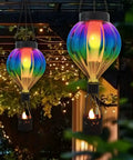 Hot Air Balloon Solar Lantern Outdoor Waterproof Hanging Glass Light With Flickering Flame Totally For Garden Backyard Patio Fence Decor Purple Gifts For Women, illuminated against trees and pergola at night