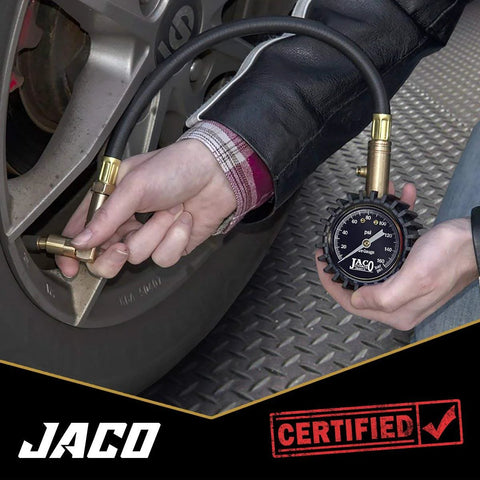 JACO EliteProPlus tire pressure gauge with dually air chuck used on a car tire; black dial gauge with brass fittings.