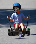 Child riding Go Kart Style Scooter Seat Attachment with colorful LED lights outdoors, wearing a helmet.