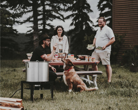 Group enjoying outdoor gathering with Seafood Boil Kit With Propane Burner And Regulator, 60 Quart Pot visible on picnic table