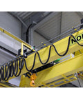 Festoon system with 80 ft flat cable; black coiled wires and orange hook on a yellow overhead crane.