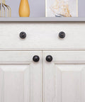 Oil Rubbed Bronze Flower Shaped Cabinet Knob Set 12 Pack For Cabinets And Drawers installed on a white double door cabinet