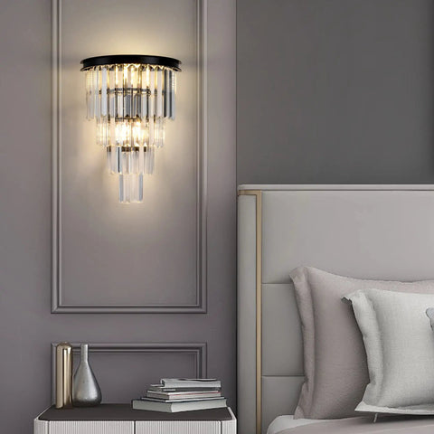 Black Crystal Wall Sconce With 4 Tier Crystal Display Modern Wall Light Fixture beside a bed in a bedroom setting.