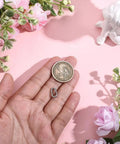 Hand holding textured 925 sterling silver oval spring gate rings carabiner clips with a coin for size comparison.